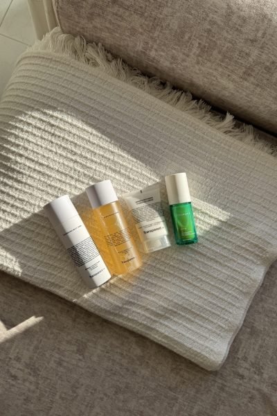 Productos de cuidado facial dispuestos sobre una manta beige con luz suave.