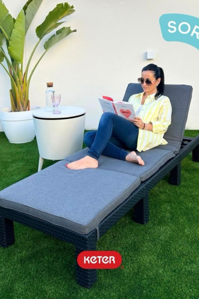 Laura Lobato leyendo en una tumbona Keter al aire libre con plantas alrededor.