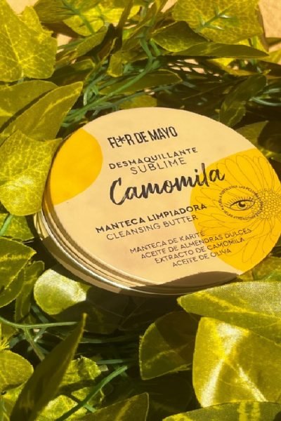 Manteca limpiadora Camomila de Flor de Mayo con fondo de hojas verdes.