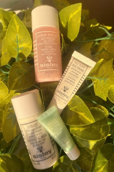 Productos de Sisley: loción tónica floral, desmaquillante y crema All Day All Year con fondo de hojas verdes.