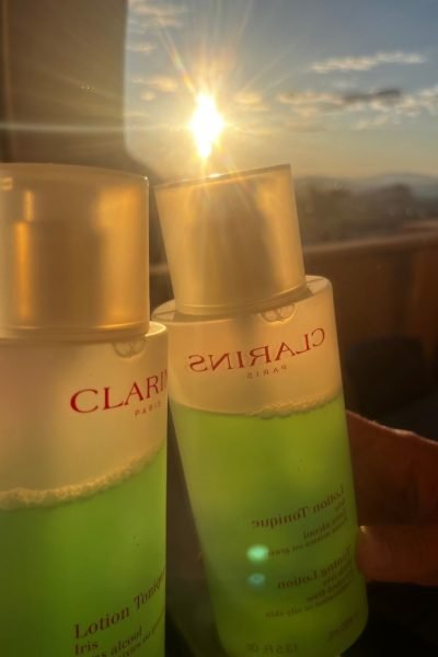 Dos botellas de loción tónica Clarins con fondo de sol brillante.