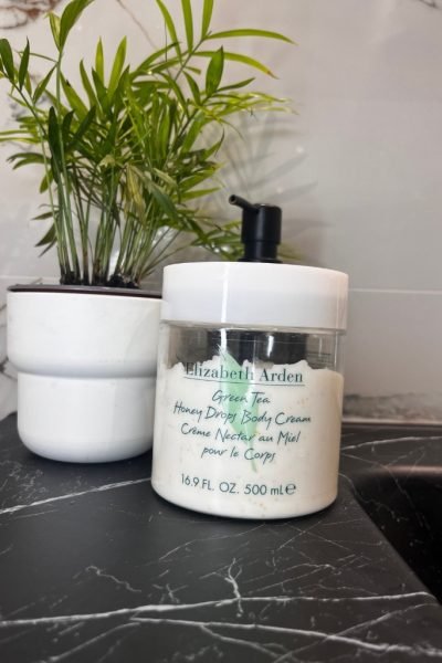 Crema corporal Green Tea Honey Drops de Elizabeth Arden con planta en el fondo.