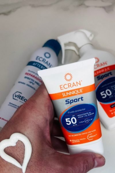 Protector solar Ecran Sunnique Sport SPF 50 con mano mostrando corazón de crema.