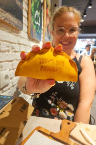 Marina García sonriente mostrando un plato de comida mientras disfruta de una bebida, creadora de contenido foodie y lifestyle.