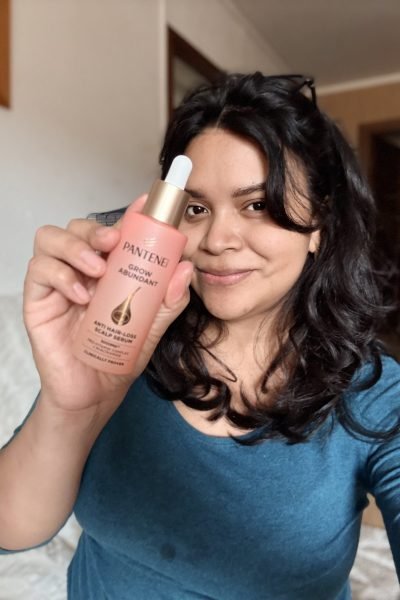 Mercedes Vergara sosteniendo el serum Pantene Grow Abundant, mostrando su textura y aplicabilidad, con sonrisa natural y fondo hogareño.