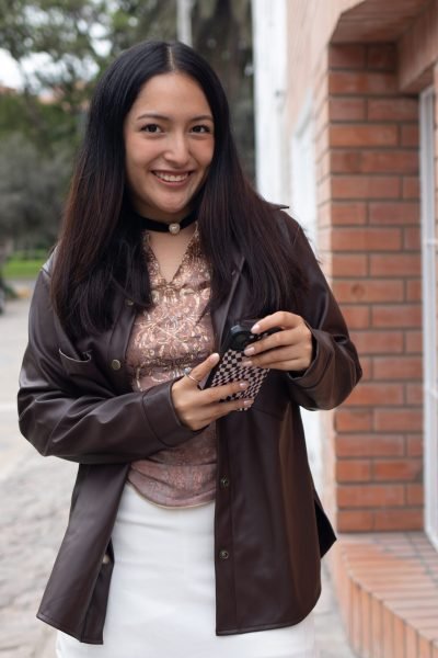 Noelia García sonriente sosteniendo un smartphone, mostrando estilo y confianza en un contenido UGC de belleza.