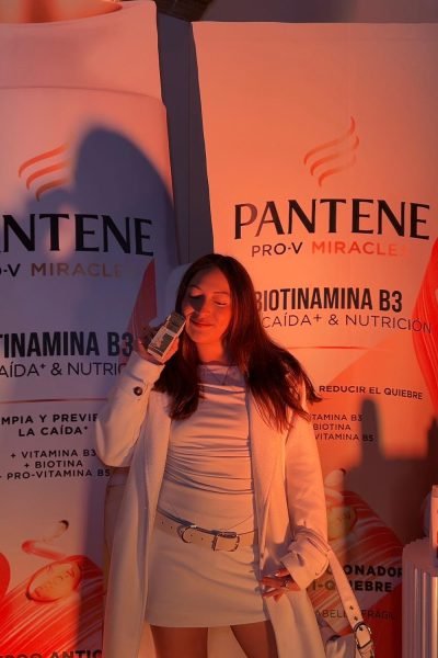 Noelia García posando sonriente con abrigo blanco y producto Pantene Pro-V Miracle