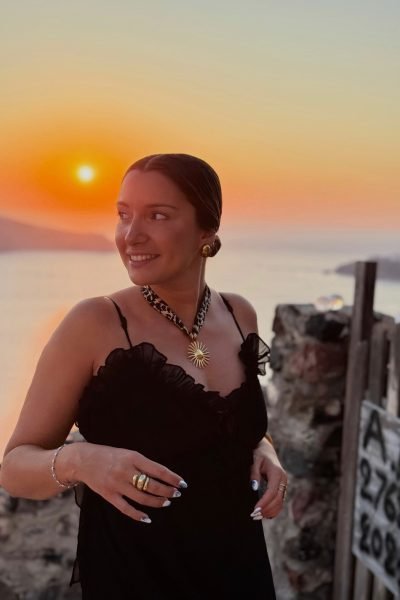 Nuria Gutiérrez, creadora de contenido lifestyle y UGC, posando con un vestido negro frente a un paisaje urbano al atardecer, mostrando estilo y elegancia.