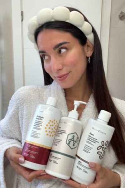 Laia posando con productos de skincare en una rutina beauty con bata blanca y look natural