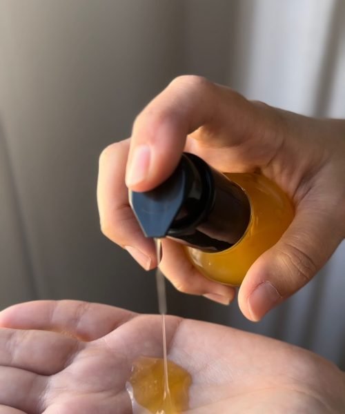 Sheila Vivas aplicando aceite cosmético en su mano, demostrando su rutina de cuidado de la piel.