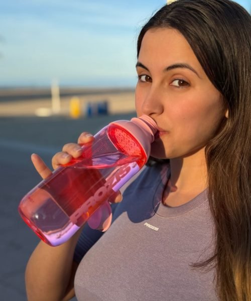 Sheila Vivas tomando agua de su botella PROZIS, con un estilo fresco y saludable en el exterior.