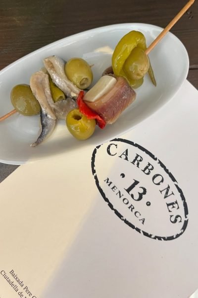 Tapas con aceitunas, anchoas y pimientos servidas en el restaurante Carbones 13 Menorca, una delicia capturada por Cristina Jiménez UGC.